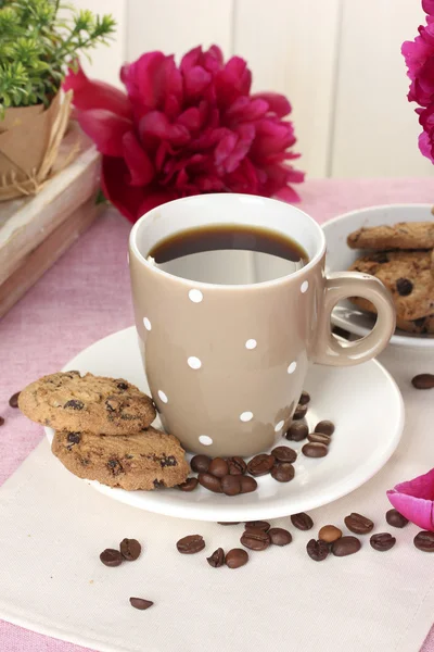 Šálek kávy, soubory cookie a květiny na stole v kavárně — Stock fotografie