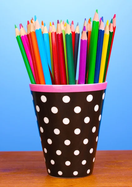 Kleur potloden in glas op houten tafel op blauwe achtergrond — Stockfoto
