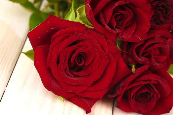 Strauß roter Rosen auf einem weißen Holztisch in Großaufnahme — Stockfoto