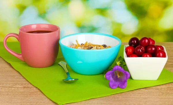Läckra flingor med körsbär för frukost på träbord på grön bakgrund — Stockfoto