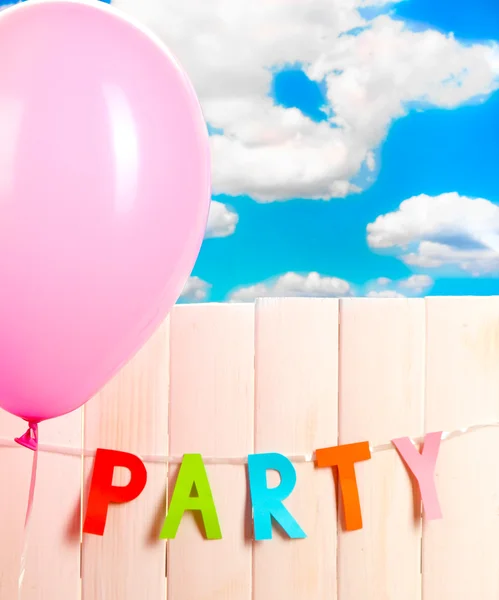 Partij. ballonnen tegen een houten hek op hemelachtergrond — Stockfoto