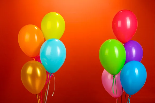 Kırmızı bir arka plan üzerinde renkli balonlar — Stok fotoğraf