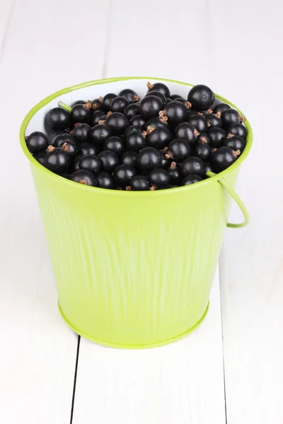 Black currant in metal bucket on wooden background — Stock Photo, Image