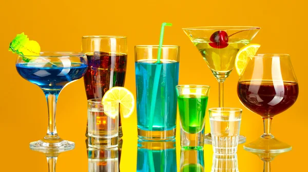 Olika alkoholhaltiga drycker på gul bakgrund — Stockfoto