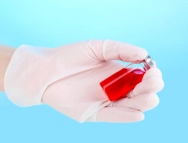 Medicinsk ampul i hånden på blå baggrund - Stock-foto