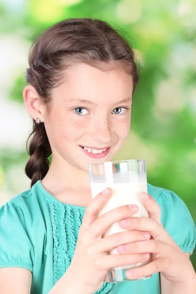 Porträt eines schönen kleinen Mädchens mit Milchglas auf grünem Hintergrund — Stockfoto