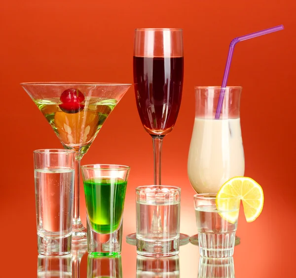 Szeroki wybór napojów alkoholowych na czerwonym tle — Zdjęcie stockowe