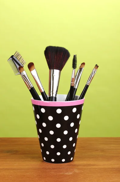 Makeup brushes in a black polka-dot cup on yellow background — Stock Photo, Image