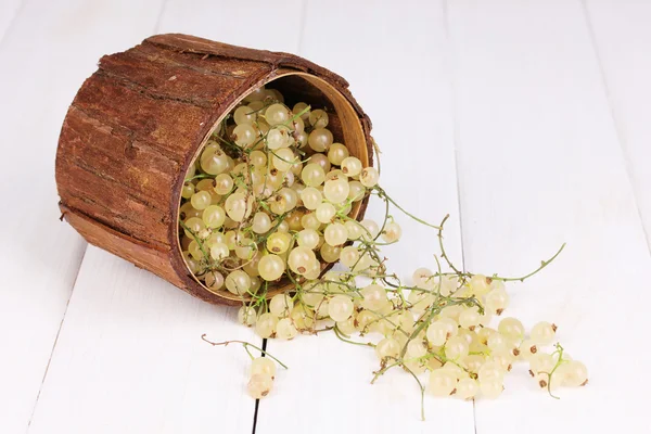 White currants in wooden cup on wooden background — Stockfoto