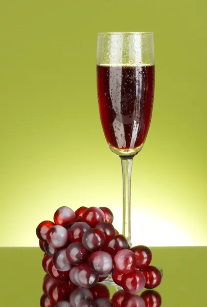 A glass of wine and grapes on green backgrund close-up — Stock Photo, Image
