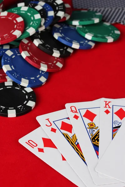 Royal flush com fichas de poker em uma mesa de poker vermelha close-up — Fotografia de Stock