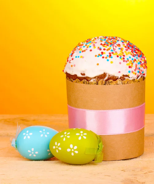 Beautiful Easter cake with eggs on wooden table on yellow background — Stock Photo, Image