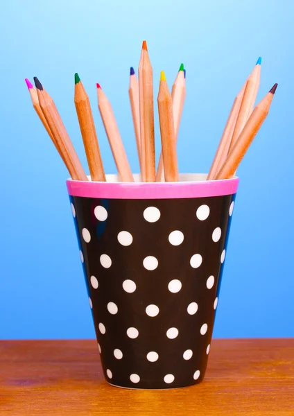 Cam ahşap masa mavi arka plan üzerinde renkli kalemler — Stok fotoğraf