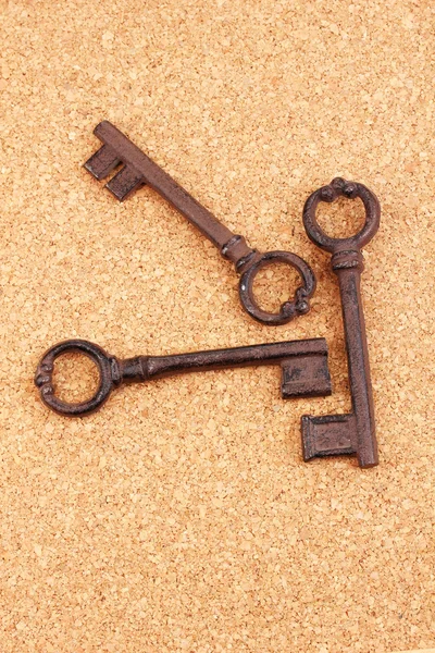 Um monte de chaves antigas no fundo de cortiça — Fotografia de Stock