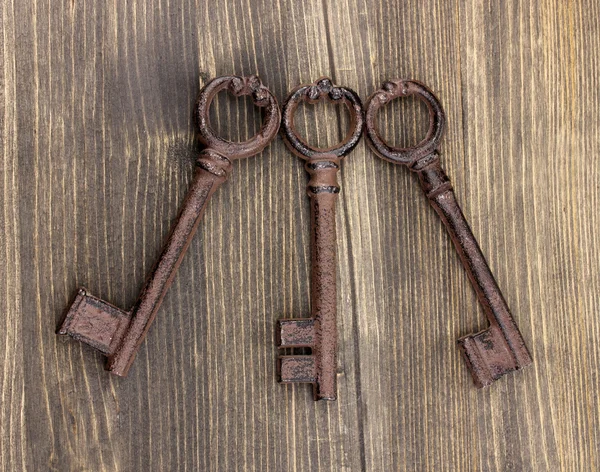 Tre antika nycklar på trä bakgrund — Stockfoto