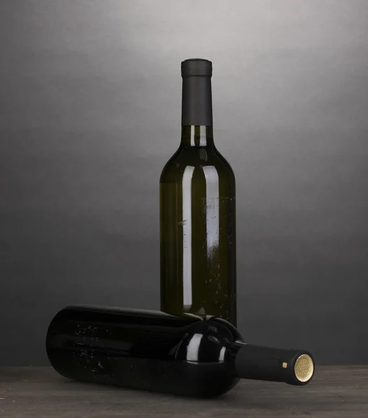Stor vinflaskor på träbord på grå bakgrund — Stockfoto