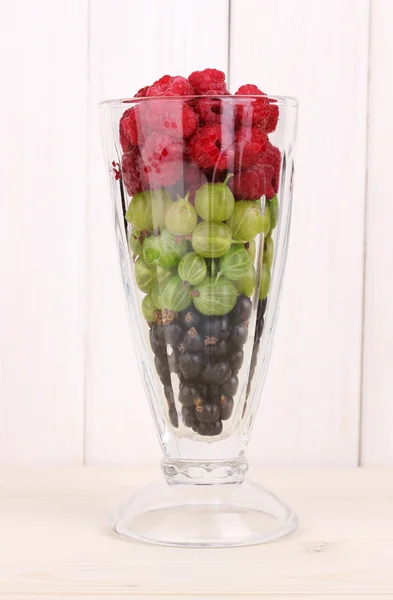 Frutas e bagas misturadas em vidro sobre fundo de madeira — Fotografia de Stock