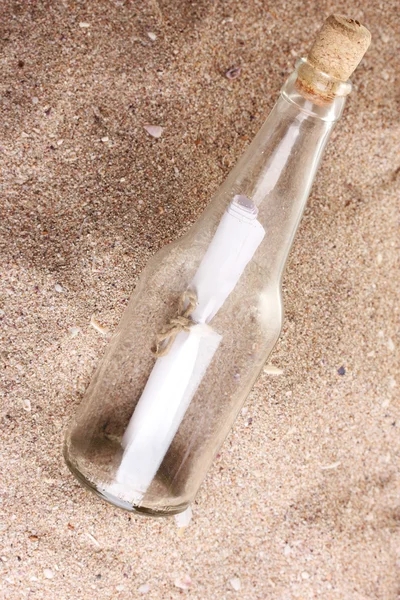 Skleněná láhev s poznámkou na písku pobřeží s mušlemi — Stock fotografie