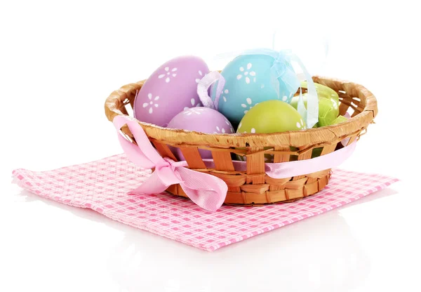 Colorful easter eggs in basket on napkin isolated on white — Stock Photo, Image