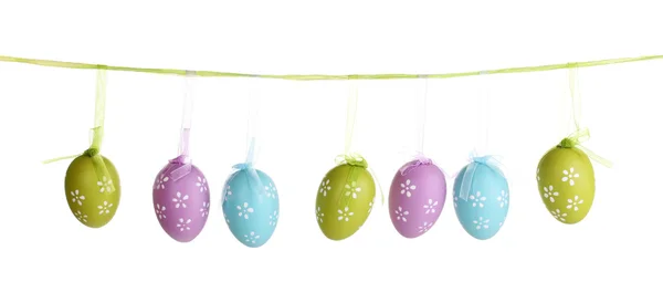 Uova di Pasqua variopinte appese su nastri isolati su bianco — Foto Stock