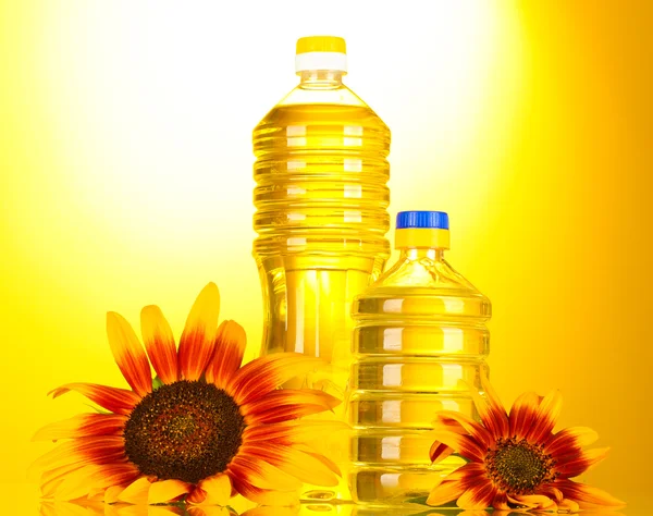 Slunečnicový olej a slunečnice na žlutém podkladu — Stock fotografie