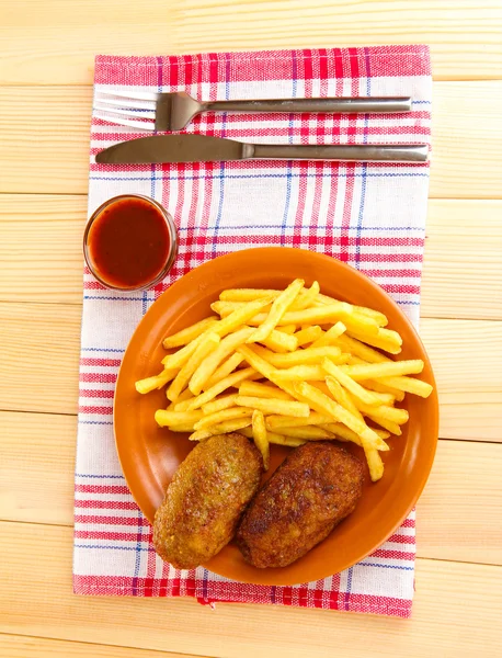 Kartoffeln Pommes mit Burgern auf dem Teller auf hölzernem Hintergrund Nahaufnahme — Stockfoto