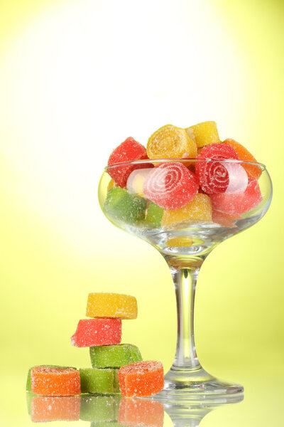Colorful jelly candies in in cocktail glass on green background