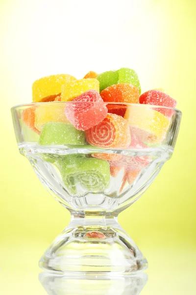 Caramelos de jalea de colores en en un tazón de vidrio sobre fondo verde — Foto de Stock