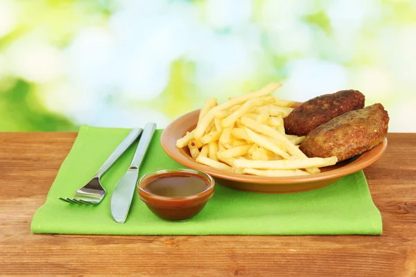 Batatas fritas com hambúrgueres no prato em fundo verde close-up — Fotografia de Stock