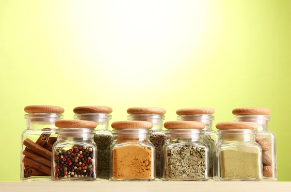 Powder spices in glass jars on green background — Stock Photo, Image