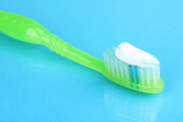 Zahnbürste mit Paste auf blauem Hintergrund — Stockfoto