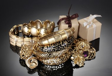 Beautiful golden jewelry and gifts on grey background clipart