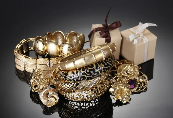 Beaux bijoux dorés et cadeaux sur fond gris — Photo