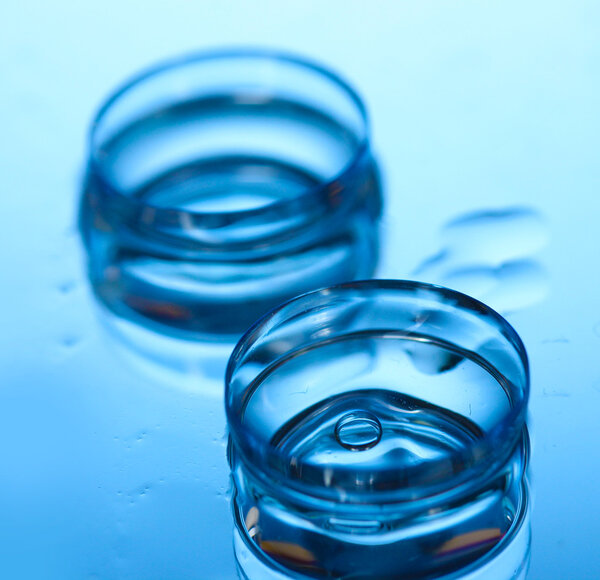 Contact lens with drops on blue background
