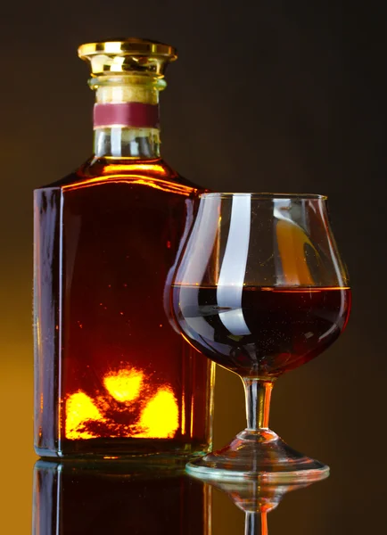 Vaso de brandy y botella sobre fondo marrón — Foto de Stock