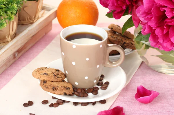 Cup of coffee, cookies, orange and flowers on table in cafe — Stock Photo, Image