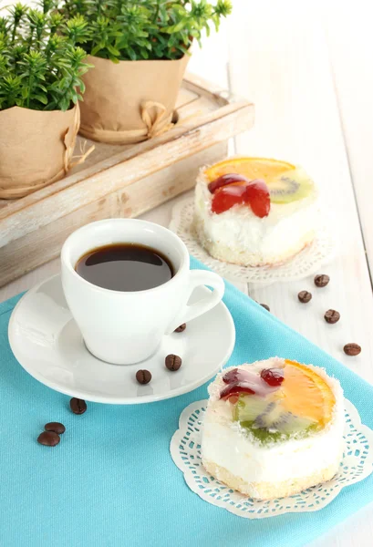 Taza de café y pasteles dulces con frutas en la mesa de madera — Foto de Stock