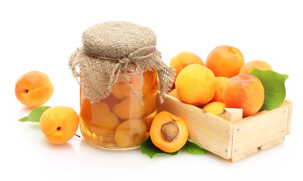 Canned apricots in a jar and fresh apricots in wooden box isolated on white — Stock Photo, Image
