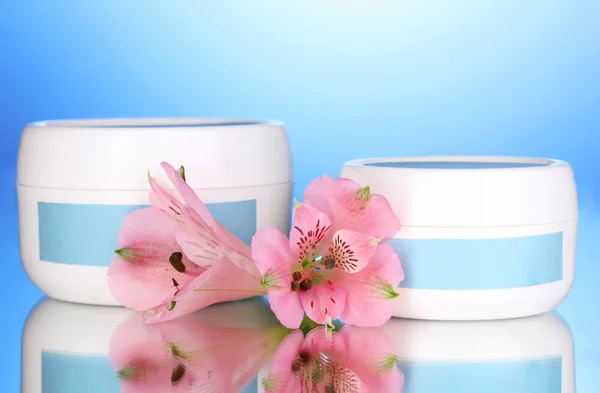 Vasi di crema con fiore su sfondo blu — Foto Stock