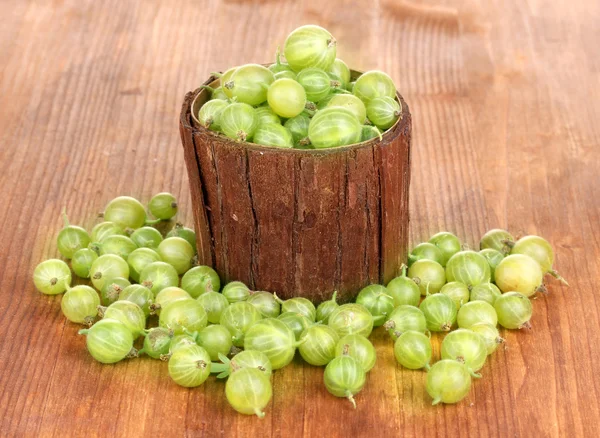 Uva spina verde in tazza di legno su sfondo di legno — Foto Stock