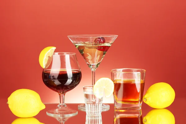 A variety of alcoholic drinks on red background — Stock Photo, Image