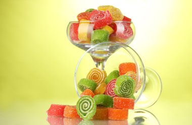 Colorful jelly candies in in cocktail glasses on green background clipart