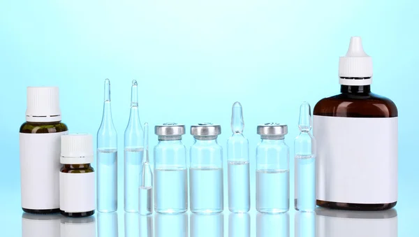 Bottiglie mediche e fiale su sfondo blu — Foto Stock