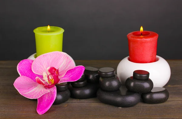 Spa stones with orchid flower and candles on wooden table on grey background — Stock Photo, Image