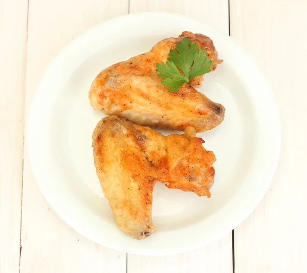 Ali di pollo arrosto con prezzemolo nel piatto su fondo di legno bianco primo piano — Foto Stock