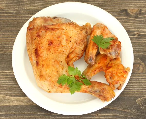 Sayap dan kaki ayam panggang dengan peterseli di piring dengan latar belakang kayu close-up — Stok Foto