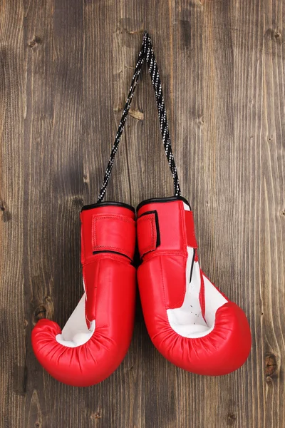 Red boxing gloves hanging on wooden background — Stock Photo, Image