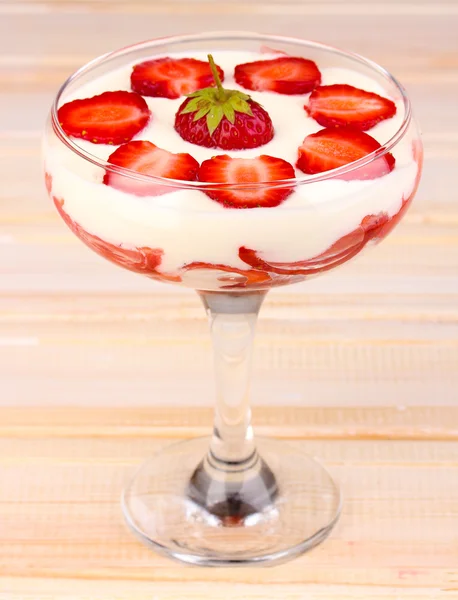 Glas van rijpe aardbeien met crème op houten achtergrond — Stockfoto