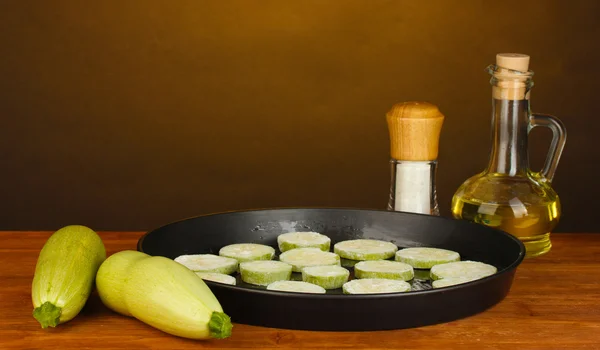 Нарізаний кабачок на сковороді на дерев'яному столі на фоні розведення крупним планом — стокове фото