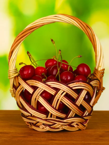 Cherry in basket on wooden table on green background — Stock Photo, Image